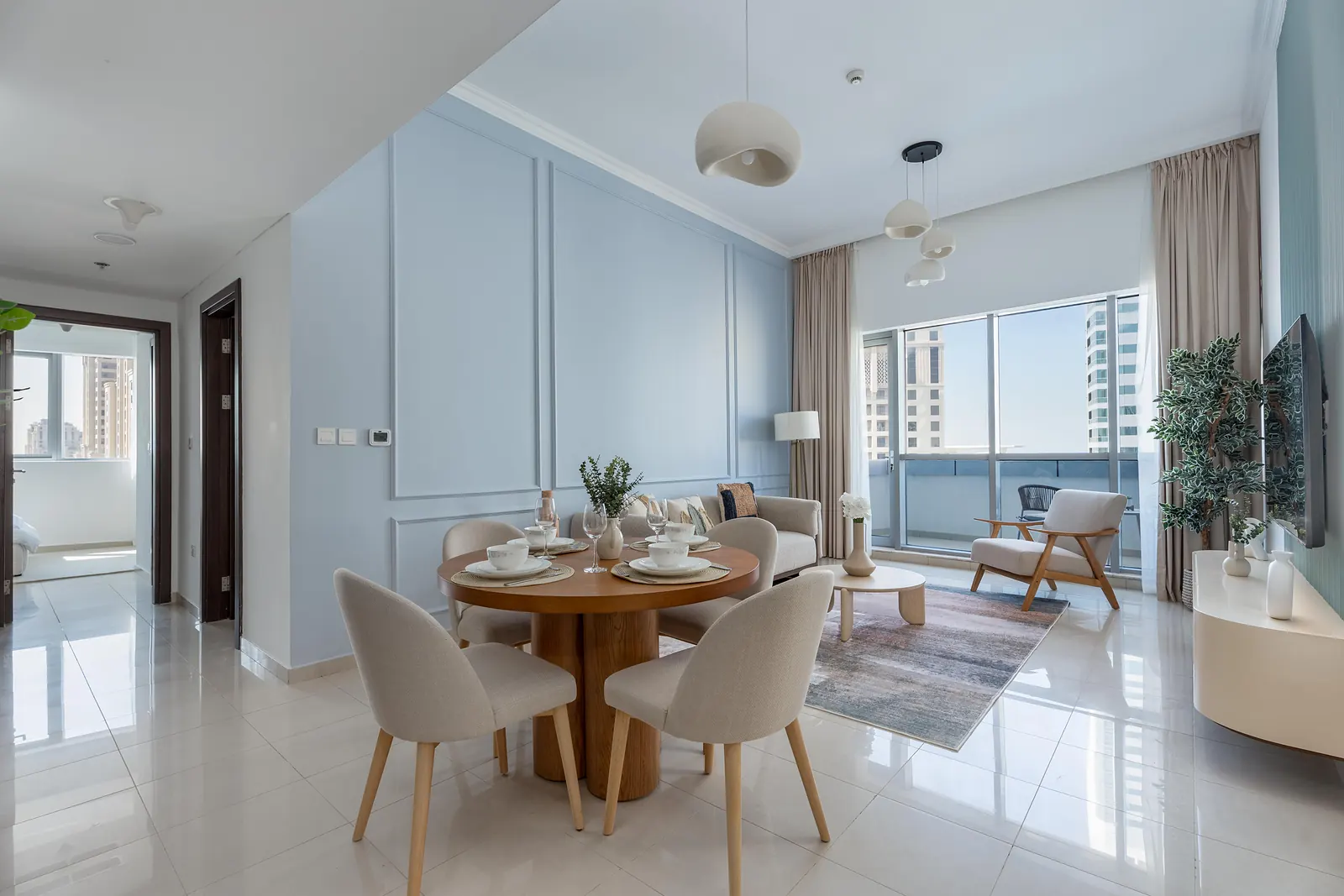 Dining table for four in front of powder-blue panel moulding, with the lounge beyond