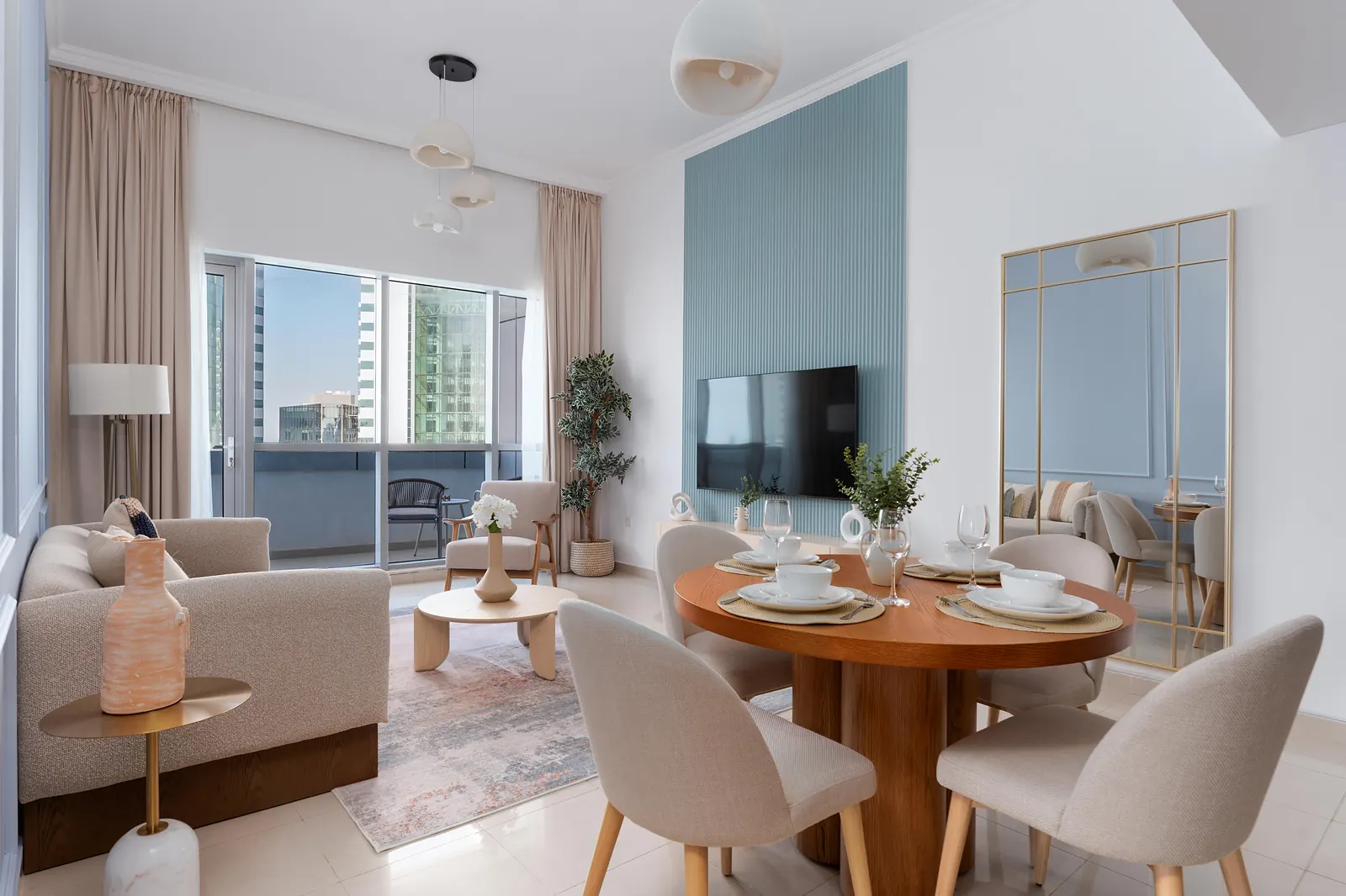 Open living and dining room with a round timber table, fluted TV wall and arched mirror