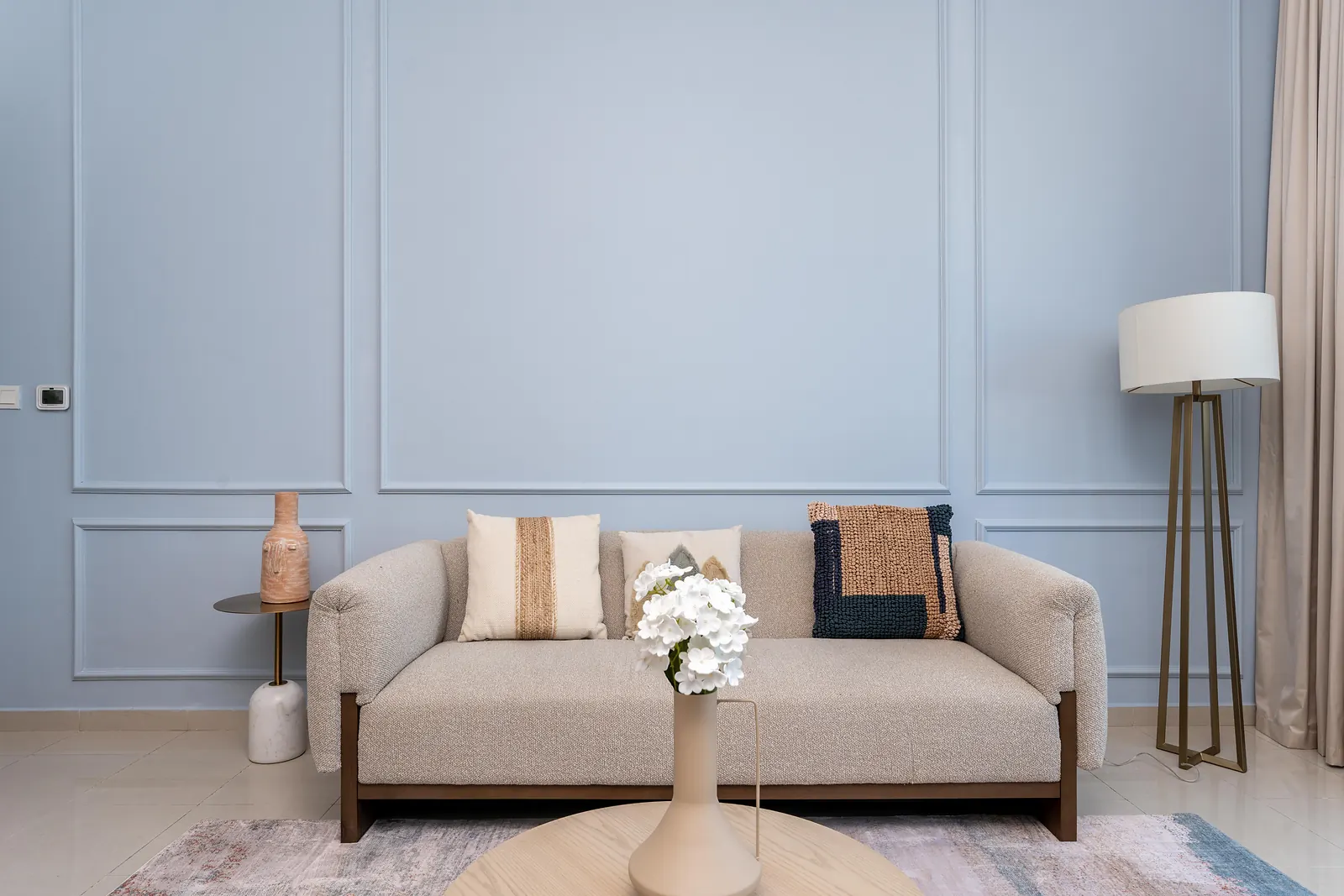 Living room with powder-blue panel moulding, a boucle sofa and a tripod floor lamp