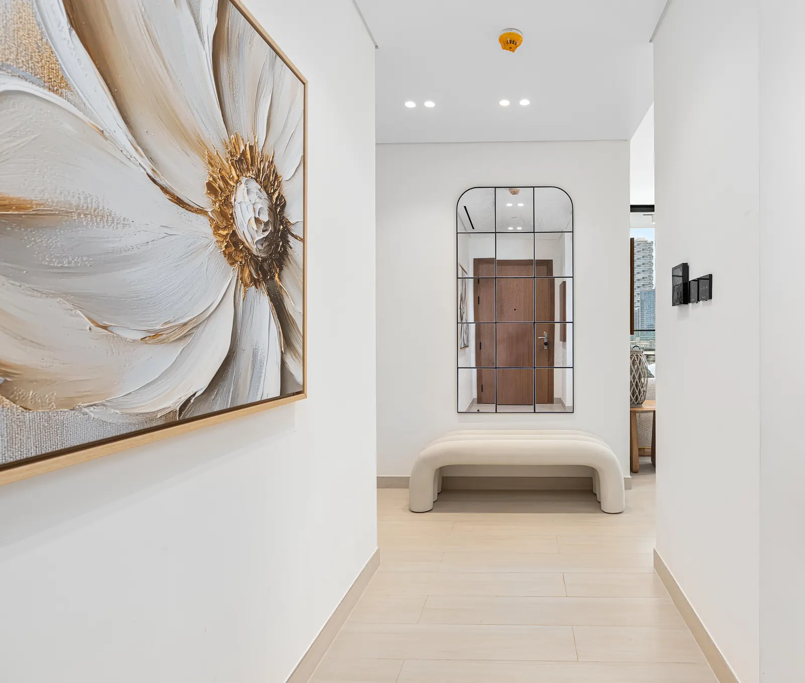Entrance hallway with an arched grid mirror, a curved boucle bench and a large floral canvas