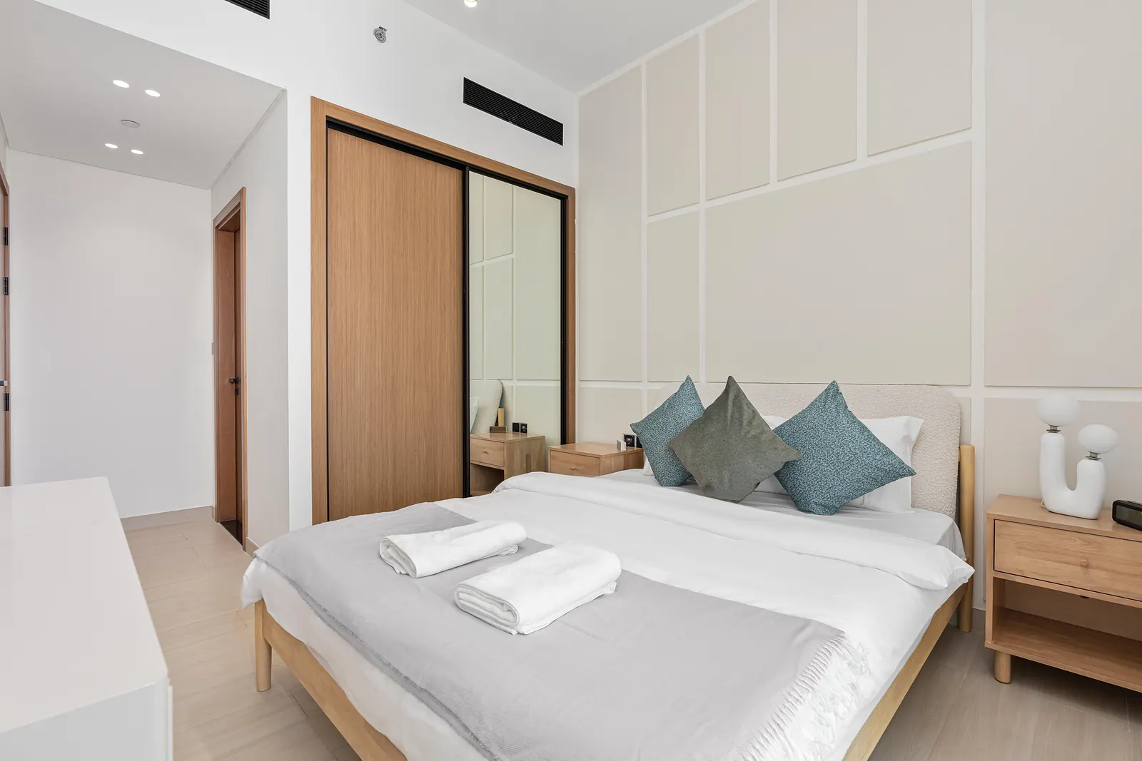 Second bedroom with cream grid panel moulding behind a boucle headboard, next to a timber wardrobe