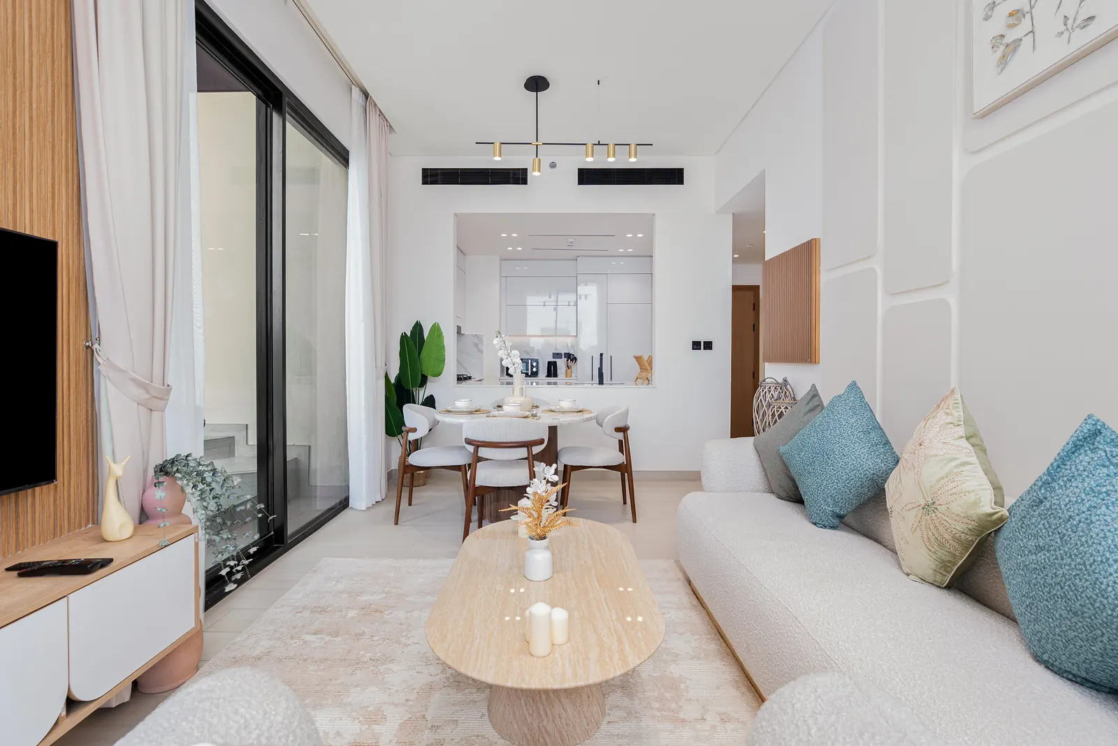 Living room opening to a round dining table, with a timber slatted TV wall and sculpted wall panels