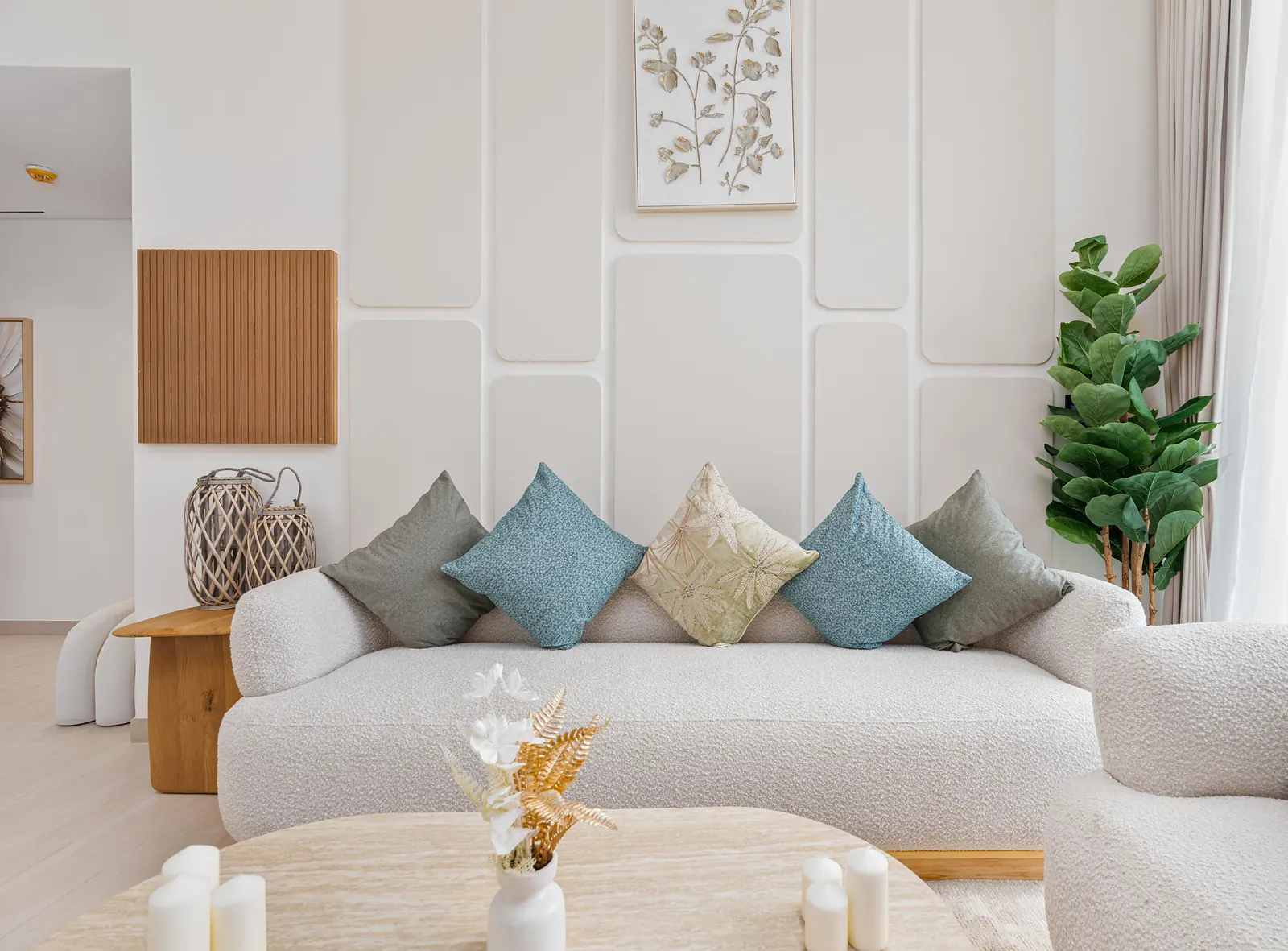 Living room with sculpted cream wall panels behind a boucle sofa with teal and sage cushions