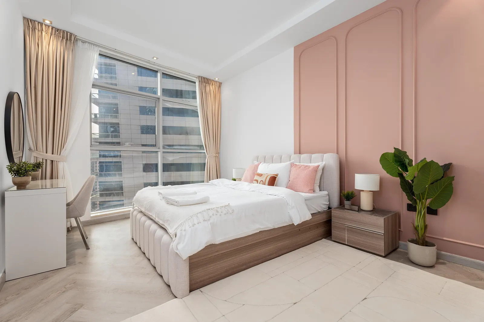 Bedroom with a blush-pink wall of arched panel moulding behind an upholstered bed
