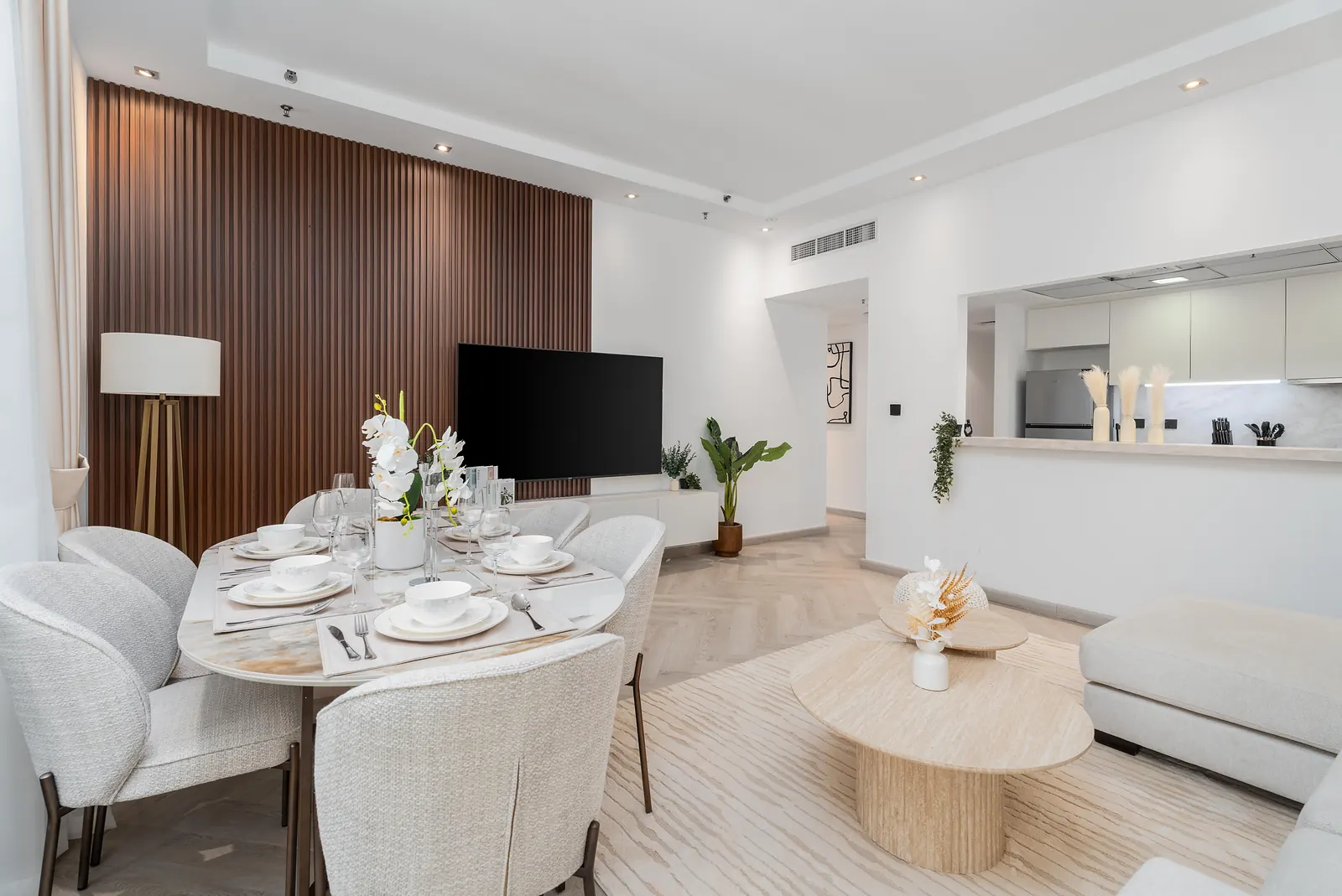Dining table for six in front of the walnut slatted wall, with an open kitchen counter behind