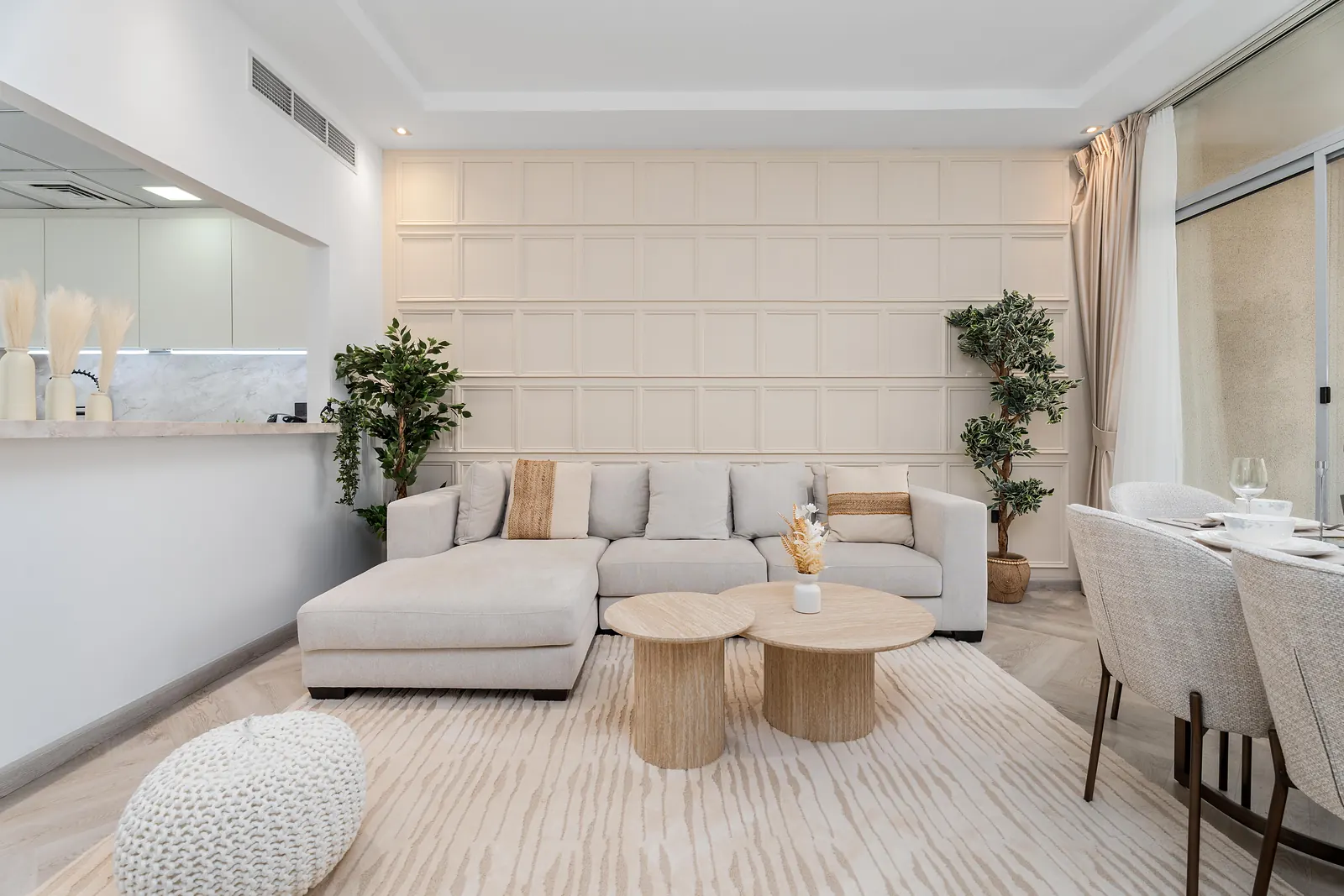 Cream grid box moulding across the wall behind an L-shaped sofa and round coffee tables