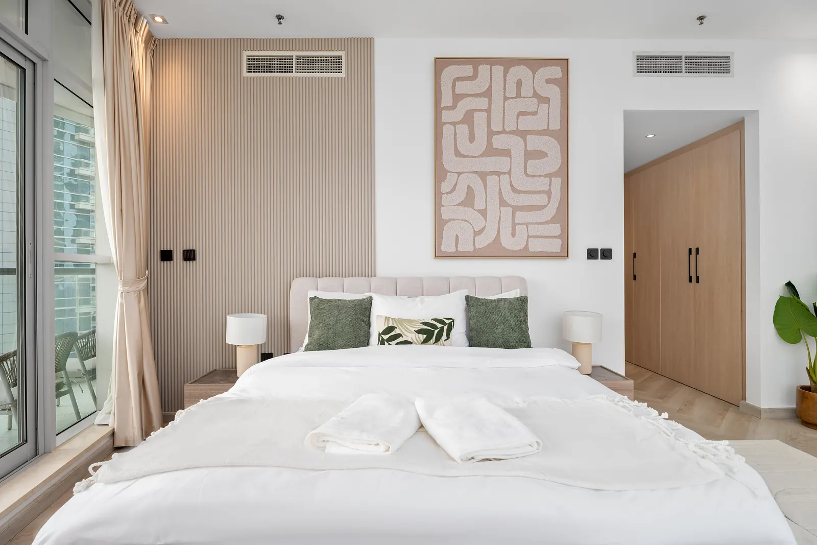 Bedroom with a slatted panel wall beside the bed, abstract textured art and a built-in wardrobe