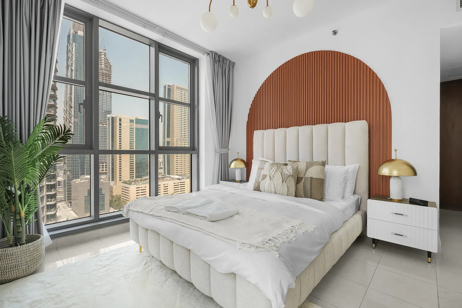 Arched terracotta slatted panel behind a channel-tufted bed