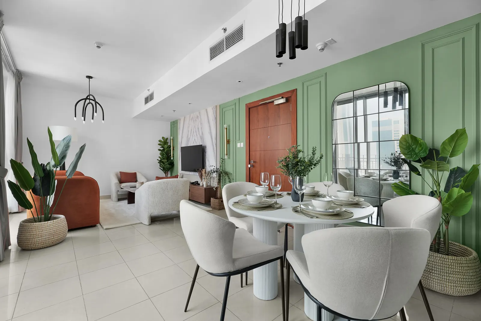 Living and dining room with sage-green box moulding, an arched grid mirror, a round dining table and a terracotta sofa