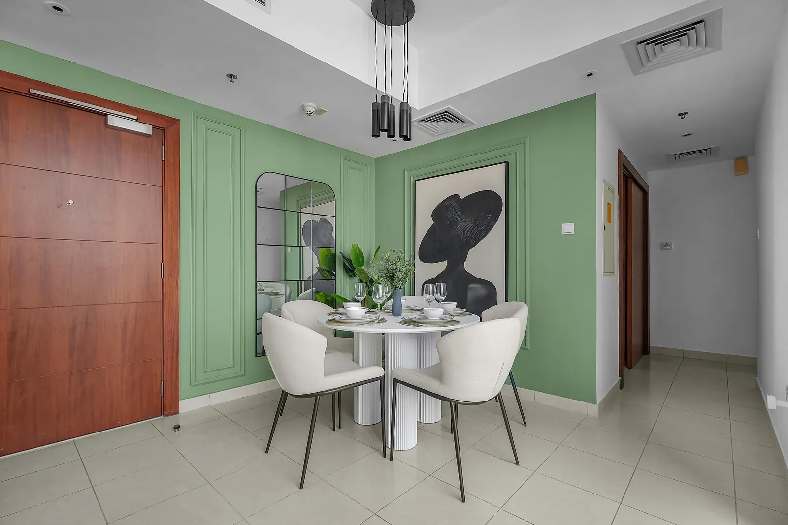 Dining corner with sage-green panel moulding framing large black and white art, and a round table for four