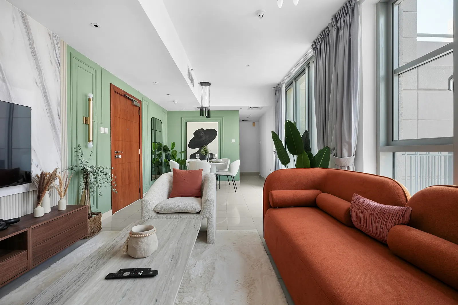 Living room with a terracotta sofa, boucle armchair, marble-effect TV wall and sage moulding